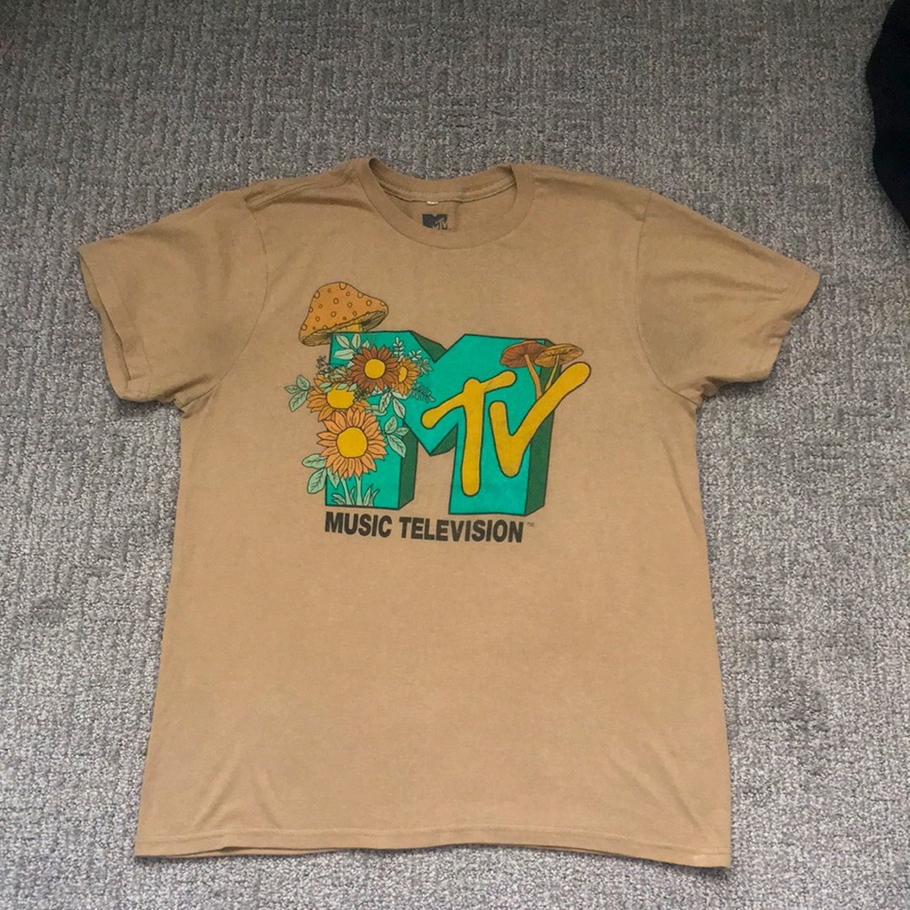 Tan graphic tee shirt with M T.V on it with flower and mushroom designs on it